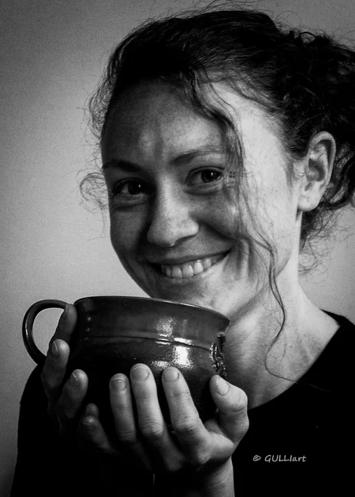 Schwarz-Weiß-Porträt einer lächelnden Frau mit Tasse