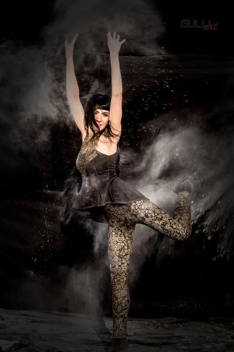 Tänzerische Pose in einer Wolke aus hellem Pulver